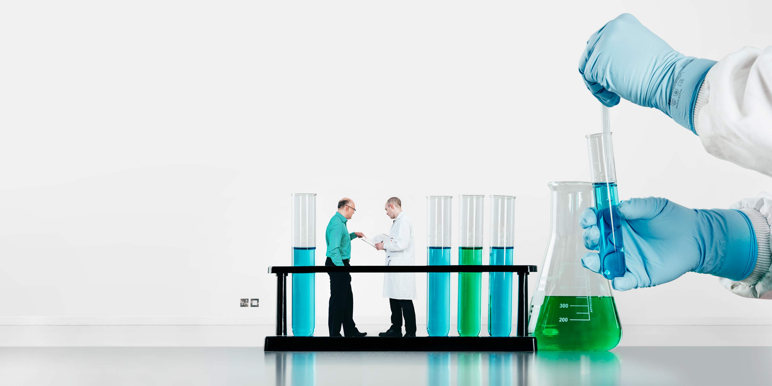 Scientist filling a test tube and people having a meeting in the background