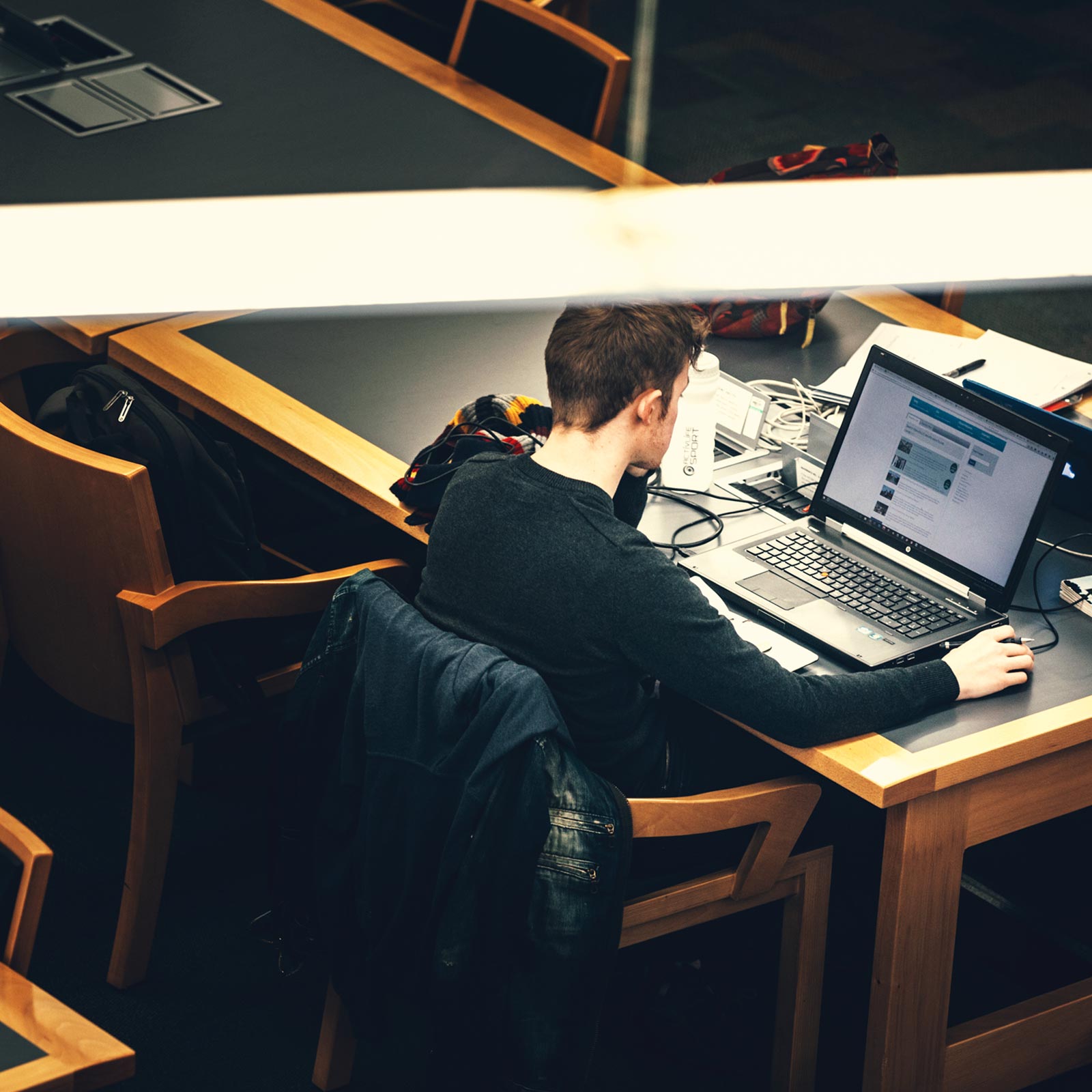 Male student on a laptop in the library at QUB