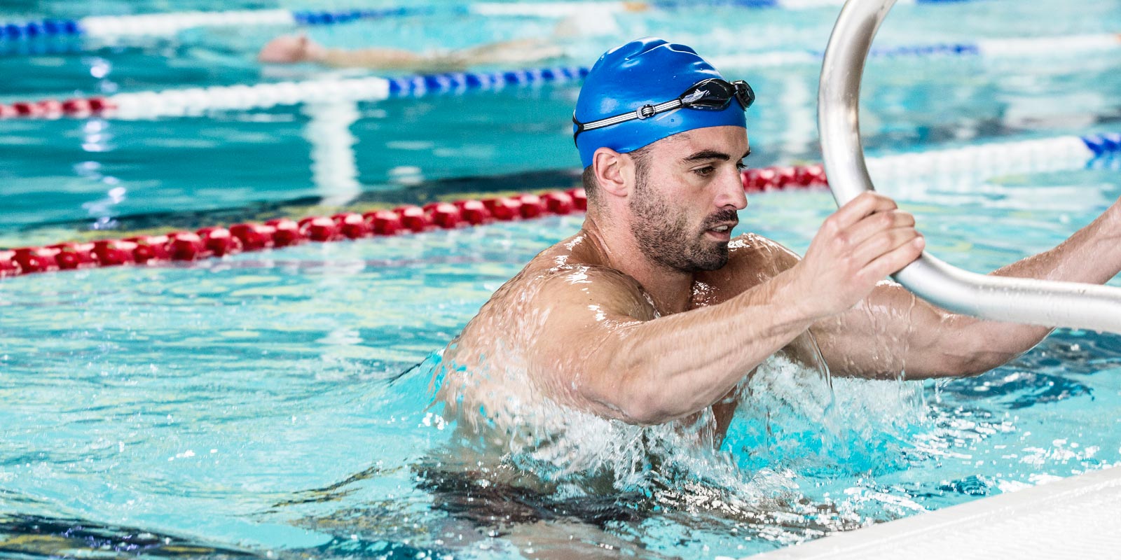Male gym member climbing out of the swimming pool